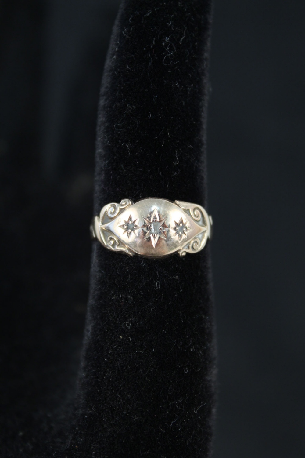 A 9ct gold ring with scrollwork detail set with three small diamonds,