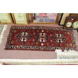 A Persian red ground rug with multiple central designs,