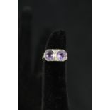 A white gold ring set with two large amethyst stones interspersed with diamonds,