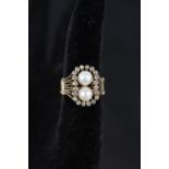 An abstract yellow metal ring set with diamond border and two pearls,