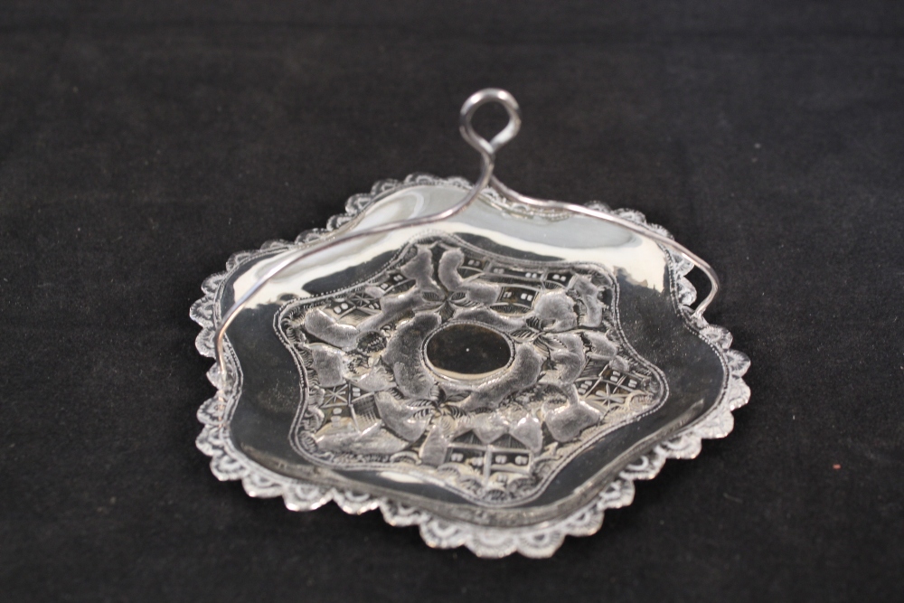 An Indian white metal dish with embossed village scene to centre with handle