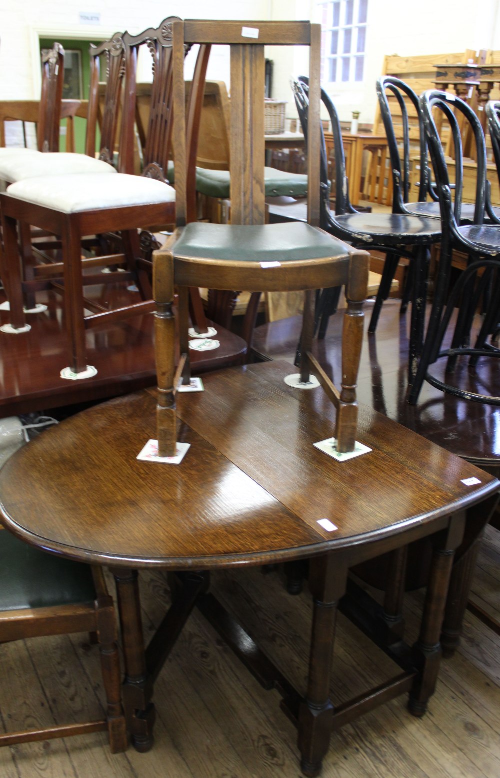 An oak oval gate leg table and three oak and leatherette chairs