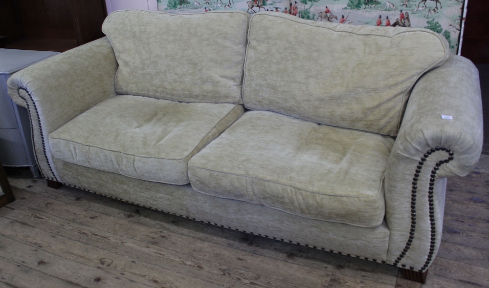 A large beige upholstered sofa with studded detail
