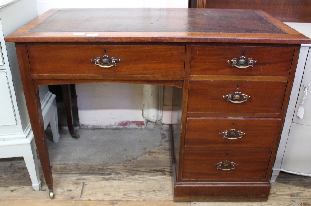 An Edwardian mahogany leather top five drawer desk on brass casters