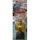 An iron base oil lamp with amber bowl and etched red glass shade