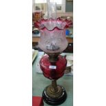 A brass column oil lamp with cranberry bowl and etched pink glass shade