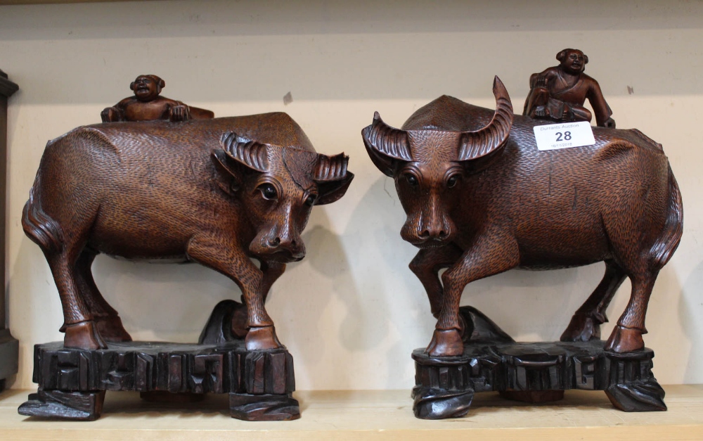 A pair of Chinese carved hardwood boys on buffaloes (chipped horns)