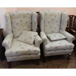 A pair of pale blue floral upholstered wingback chairs with oak claw and ball feet