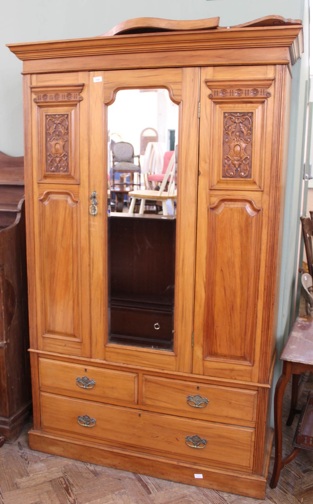 An Edwardian satinwood carved double wardrobe with three drawers below