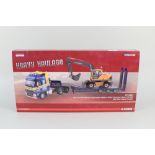 A boxed Corgi heavy haulage Volvo F H Nooteboom step frame trailer and Volvo excavator wheel EW180B