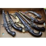 A box of seven decorative pistols and a powder flask