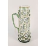 A German green glass jug with raised roundels and leaf decorated enamel decoration