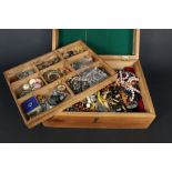 A wooden box with costume jewellery contents including rings, necklaces,