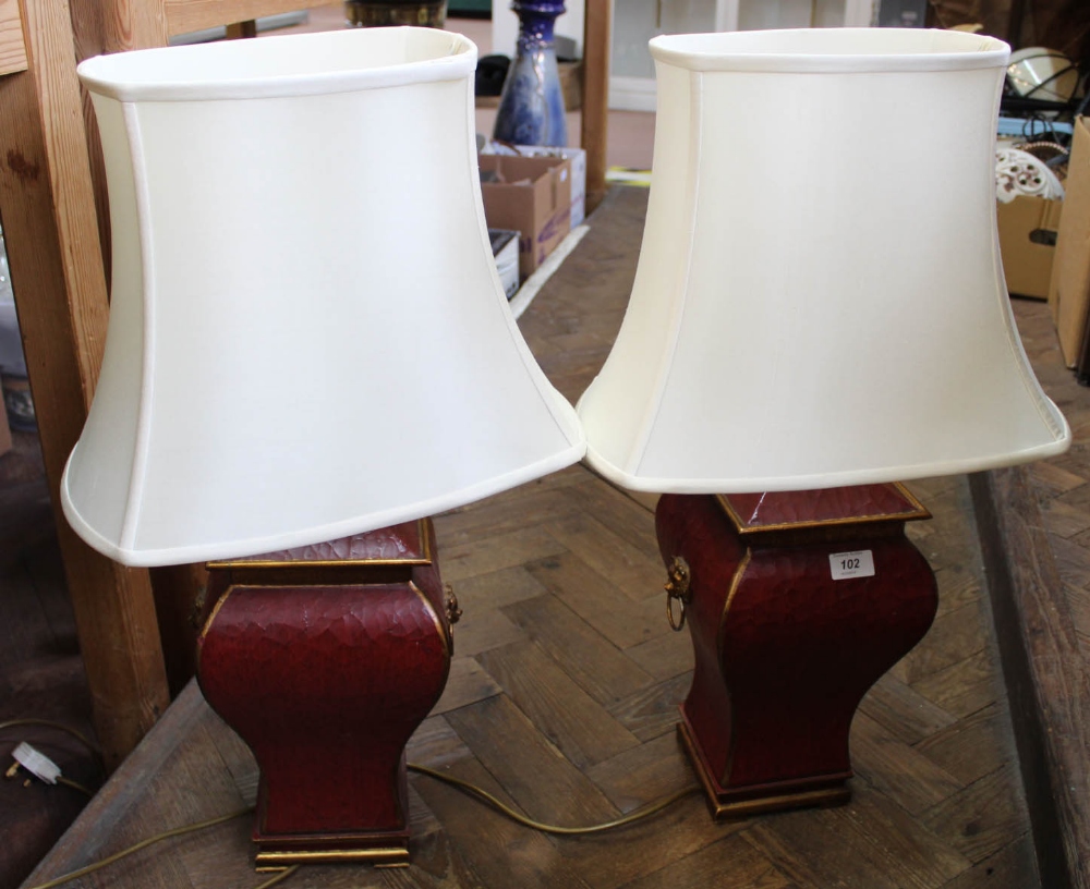 A pair of maroon and gilt table lamps with lion ring handles