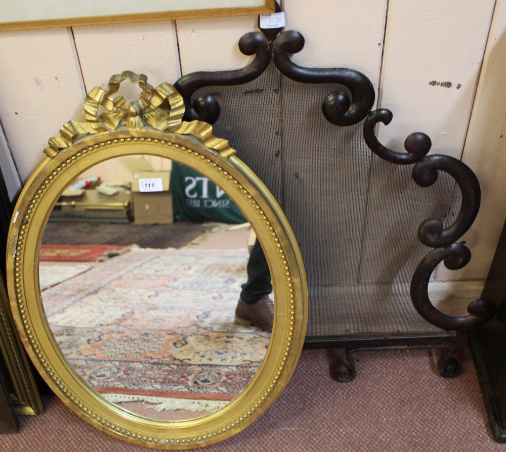 An oval gilt wall mirror plus a shaped metal and mesh fire screen