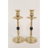 A pair of Arts and Crafts brass candlesticks with drip trays,