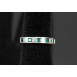 An 18ct white gold half eternity ring set with alternating square cut emeralds and diamonds,