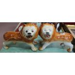 A pair of Victorian pottery standing lions (leg repairs)