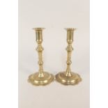 A pair of 18th Century seamed brass candlesticks with knopped stems and petal shaped bases,