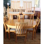 A modern extending beech dining table and six matching cream upholstered dining chairs (including