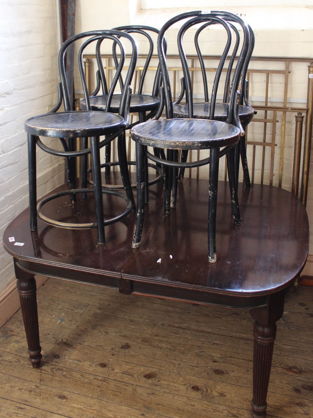 A set of four black painted bentwood cafe chairs and a mahogany dining table with reeded legs
