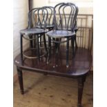 A set of four black painted bentwood cafe chairs and a mahogany dining table with reeded legs