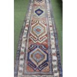 A late 19thC middle eastern rug, with a repeat geometric pattern, predominantly in red and blue,