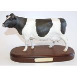 A Royal Doulton matt Friesian cow, on wooden plinth, 28cm wide.