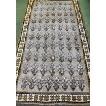An early 20thC rug, in repeat geometric floral pattern predominantly in cream, yellow and blue,