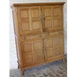 An oak Arts & Crafts freestanding cupboard, the rectangular overhanging top raised above two