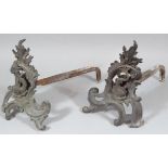 A pair of cast iron fire dogs, with scroll floral and serpent fronts and shaped backs, probably