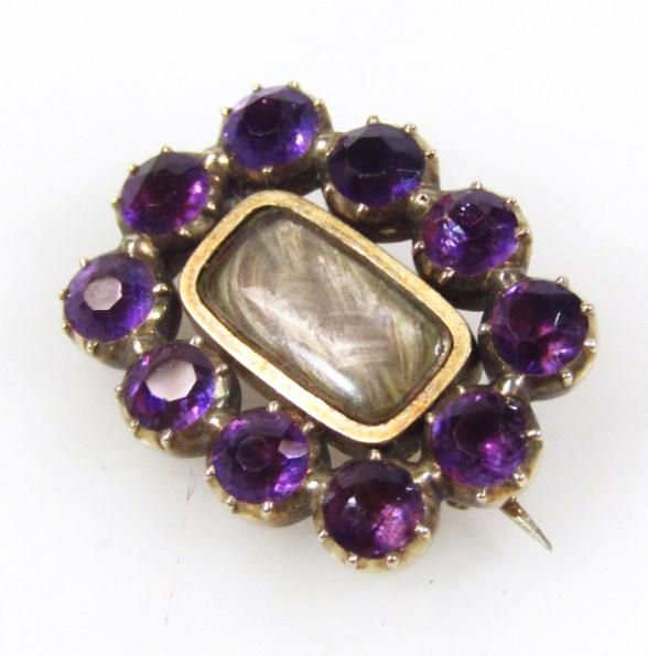 A 19thC brooch, with shaped oval outline, set with purple stones, with an entwined lock of hair