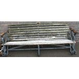 A cast iron and wooden slatted four seater bench, with turned ends, solid metal arms, slatted
