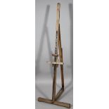 An early 20thC easel, with articulated centre on a T-shaped base, 134cm high.