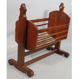 A 20thC carved wooden crib, the articulated centre supported by shaped top supports, on scroll feet,