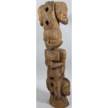 An early 20thC African tribal totem group, formed as figure with elaborate head dress, above two