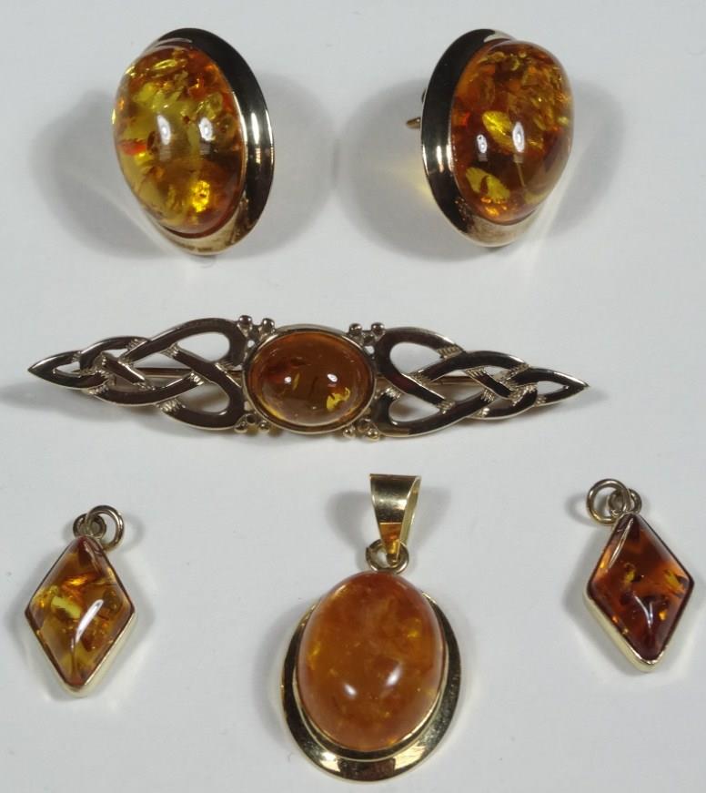 A 9ct gold amber brooch, of shaped part pierced outline, centred with a raised oval stone, 5cm wide,