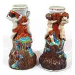 A pair of 20thC majolica style lamp bases, each cherubic and naturalistic stem, profusely polychrome