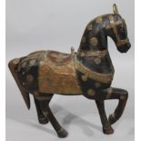 An Arabian carved wooden figure of a horse, raised with elaborate metal tack, saddle, etc, with