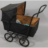 An early 20thC child's pram, with pressed leather articulated canopy, shaped body, and truckle wheel