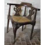 An early 19thC oak and elm corner chair, with pierced splats, inverted front support, cylindrical