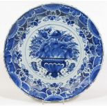 A late 17thC English Delft blue and white charger, of circular outline, centred with a basket of
