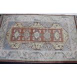 A 20thC Turkish rug, in a repeat geometric floral pattern, predominantly in blue, cream and red,