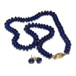 A lapis lazuli necklace with stud earrings, each bead of circular form, on blue string, with a