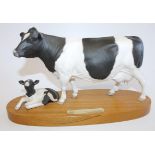 A Royal Doulton Friesian cow and calf figure group, matt, on wooden plinth, 32cm wide.