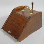 An early 20thC oak coal box, with brass mounts, handle and (removable) shovel, the hinged lid