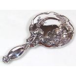 An Edwardian Art Nouveau silver hand mirror, of shaped outline, raised with flower heads and petals,