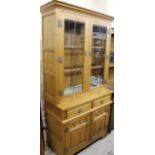 A modern light oak finish Old Charm display cabinet, the upper section with over hanging cornice