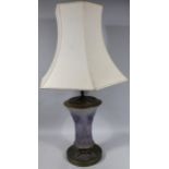 A mid 20thC amethyst glass and metal table lamp, the inverted body raised with flowers in purple and