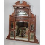 An Edwardian walnut over mantel mirror, the carved cornice raised above a crescent bevelled glass,